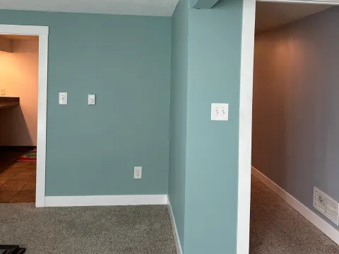 Interior room painted in a calming blue green color with white trim and accent beam