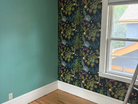 Accent wall featuring decorative floral wallpaper installation paired with painted teal walls